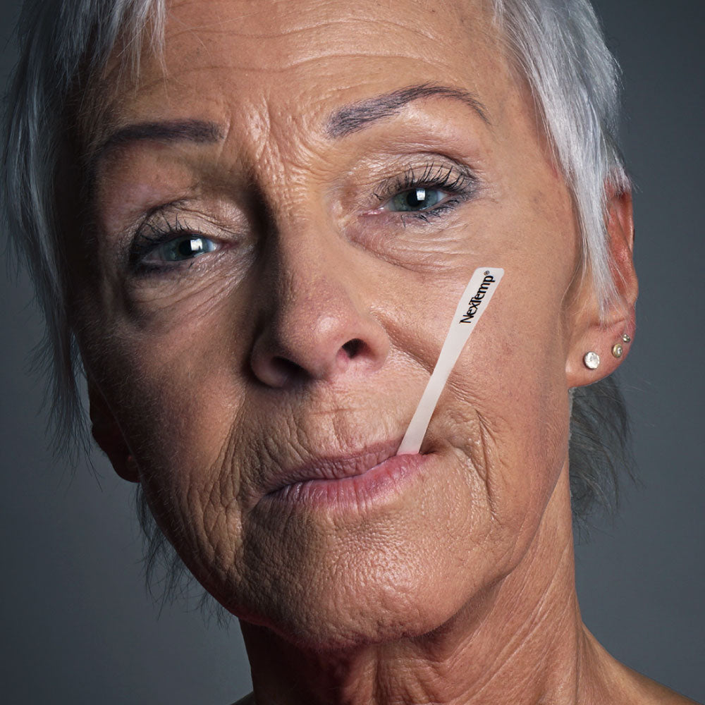 Older Woman Using NexTemp Disposable Thermometer Under Lip for Temperature Check